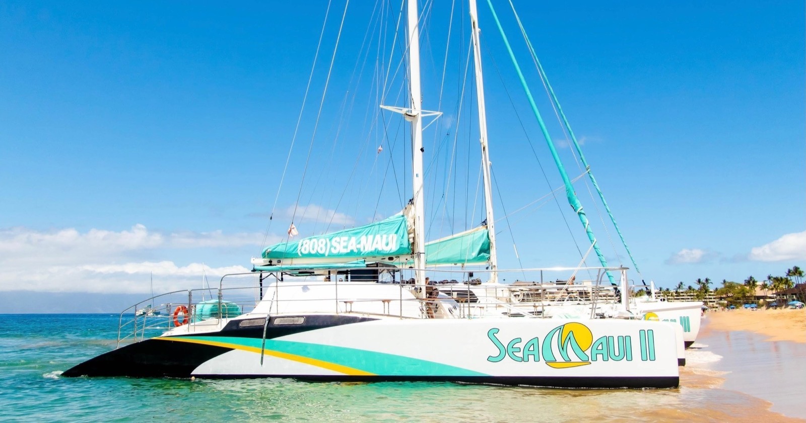 Sea Maui II catamaran resting on the sand at Kaanapali Beach with turquoise water and blue sky