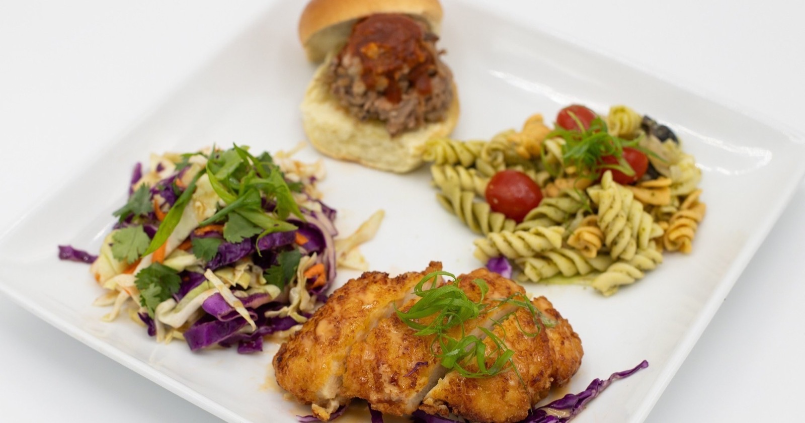 Plate of pupus with a pork slider, Asian slaw, fried chicken cutlet and pasta salad