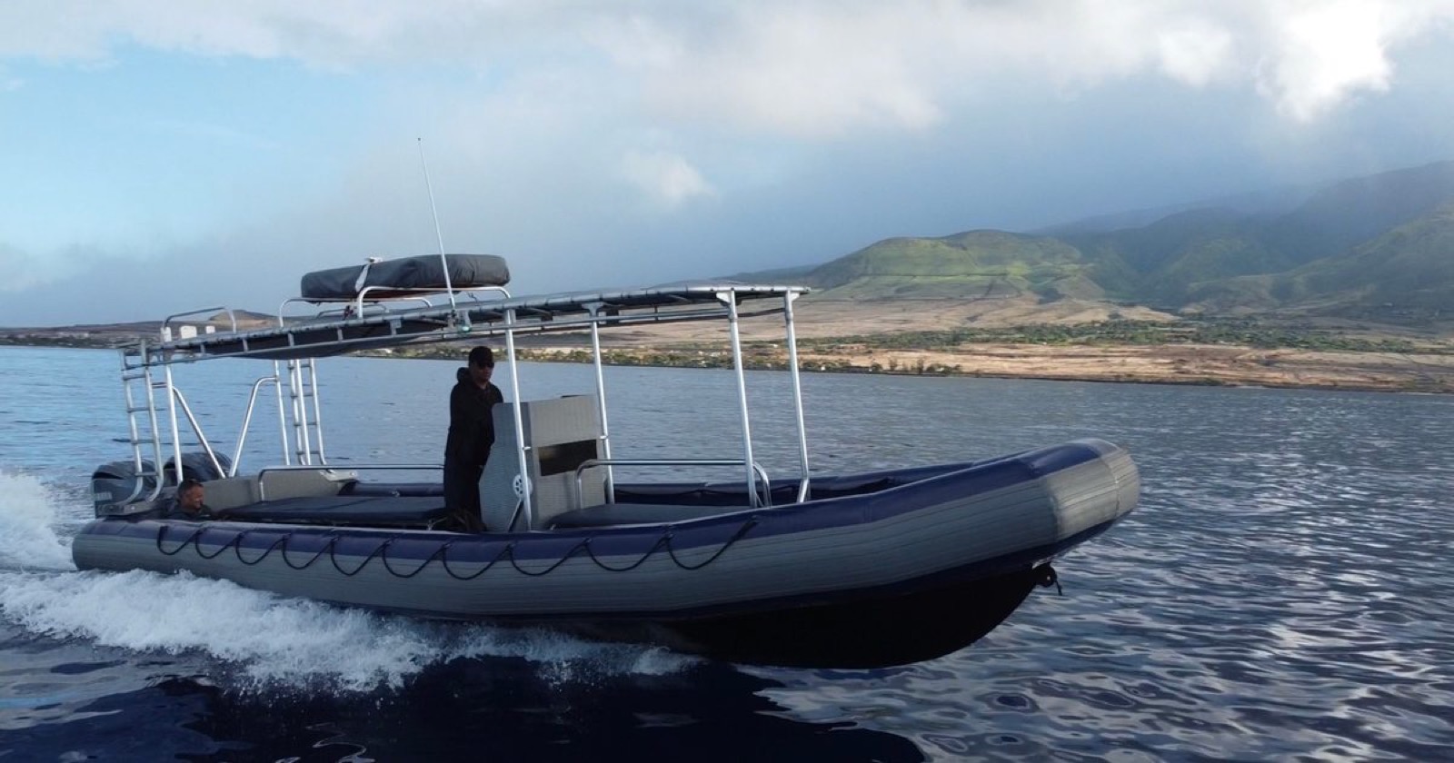 The Maui Whale Adventures raft running along the West Maui coast with its overhead shade and a captain at the console
