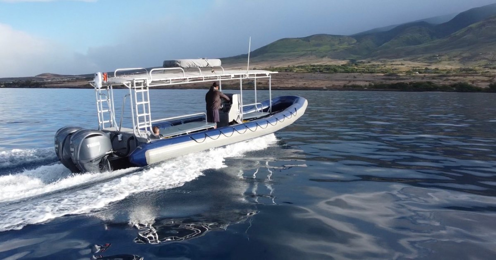 Rear view of the twin-engine raft under way with two outboard motors and the West Maui Mountains behind
